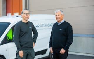 Två personer som står framför en vit bil med Airwatergreens logotyp